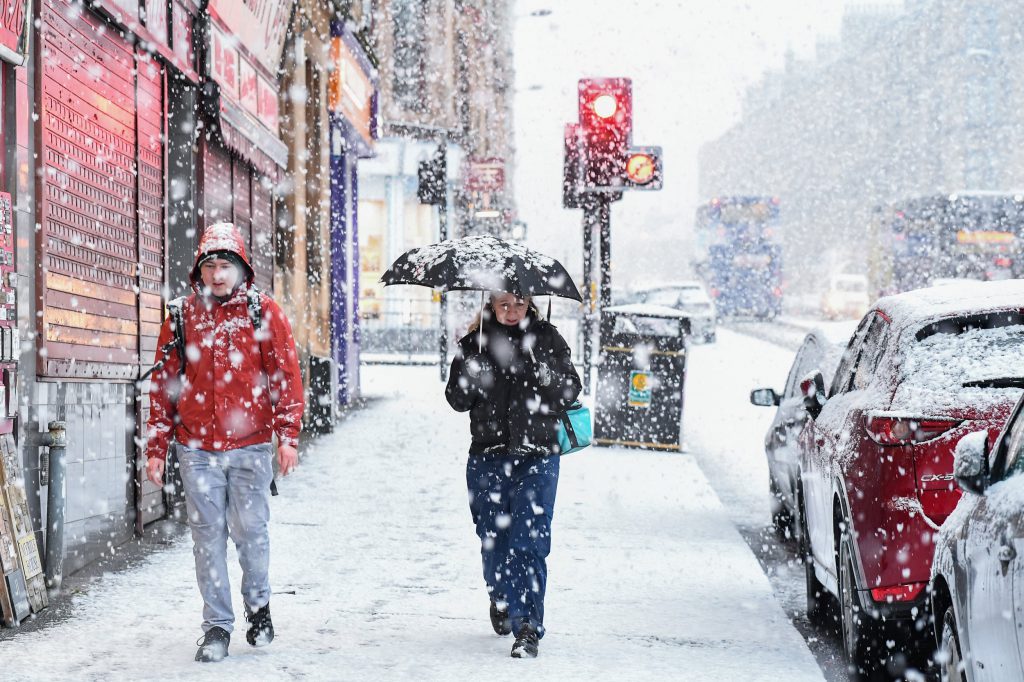 two people walking through the snow with an umbrella