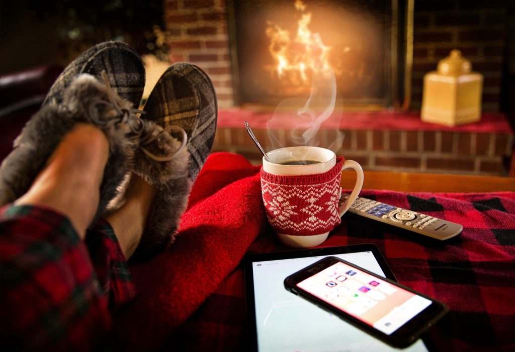 Somebody wearing slippers with a hot cup of drink, chilled out by a cosy fire in their living room