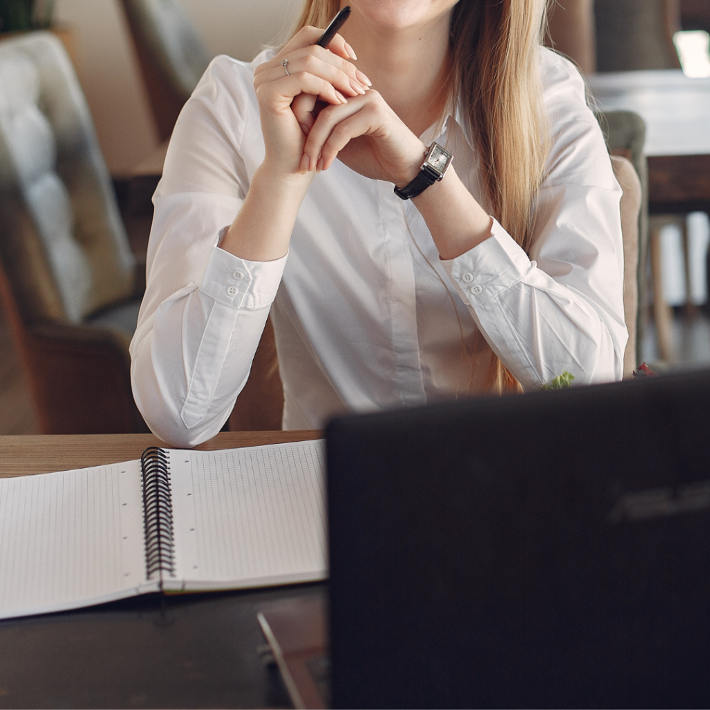 Female with a pen in her hand, laptop and notebook open