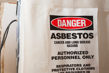 White plastic sheeting with a 'Danger Asbestos' sign, warning of cancer and lung disease hazards. The sign indicates that only authorized personnel with respirators and protective clothing are permitted in the area.